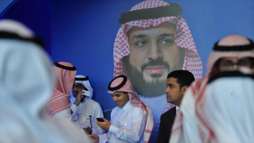 Saudíes frente a un cartel del príncipe heredero Muhamad bin Salman durante un foro en Riad, capital del país árabe, 15 de noviembre de 2017. (Foto: AFP)