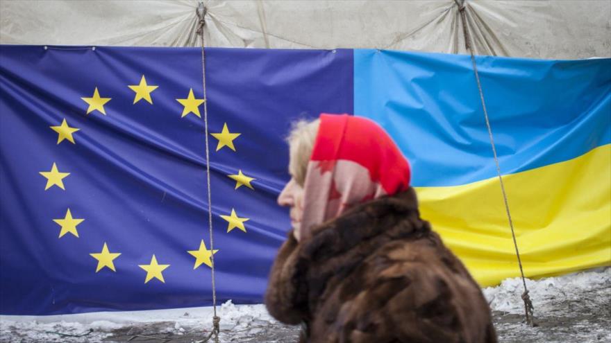Una mujer pasa junto a una tienda que muestra las banderas de la Unión Europea y de Ucrania en Kiev, 28 de enero de 2014.