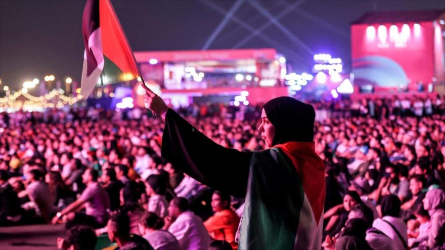 Un fanático de fútbol ondea bandera palestina en transmisión en vivo de un partido durante el Mundial de Catar en Doha, 26 de noviembre de 2022. (Foto: AFP)