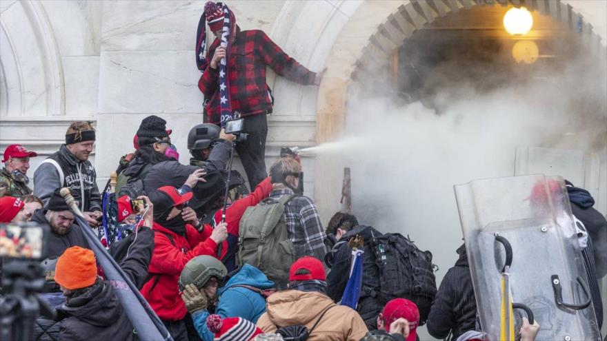 Manifestantes usan gases lacrimógenos mientras se enfrentan a la policía que intenta ingresar al edificio del Capitolio por las puertas principales el 6 de enero de 2021, en Washington, D.C.