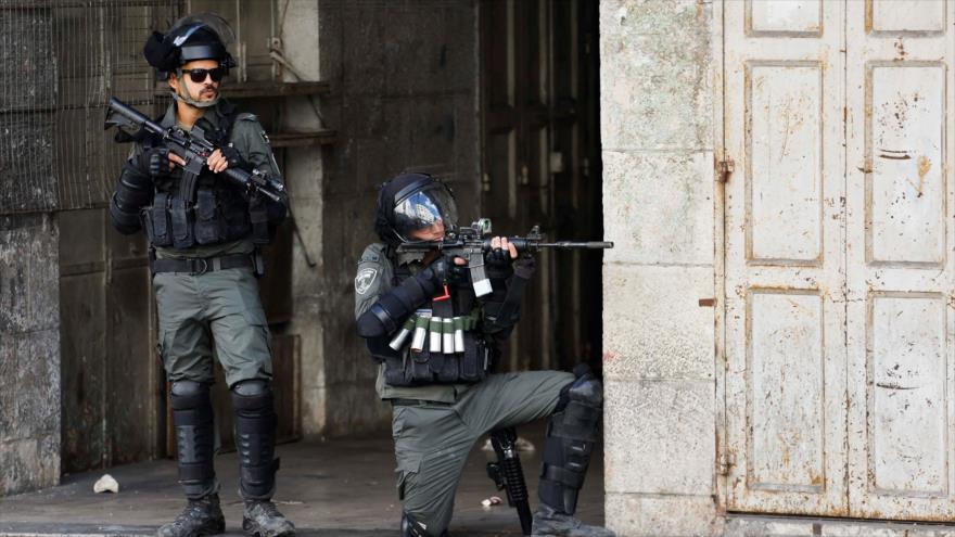 Un soldado israelí apunta su arma contra palestinos en la ciudad cisjordana de Al-Jalil (Hebrón), 14 de octubre de 2022. (Foto: Reuters)