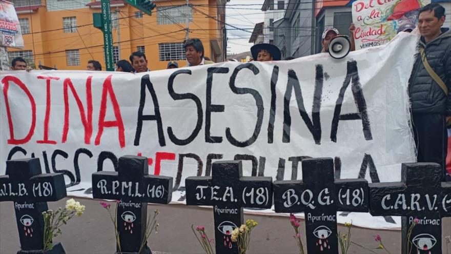 Manifestantes peruanos muestran una pancarta contra la presidenta Dina Boluarte.