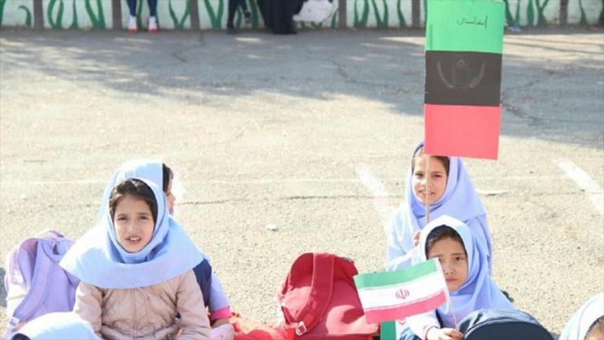Estudiantes afganos, portando banderas de Irán y Afganistán, durante una fiesta en una escuela en Teherán, Irán.