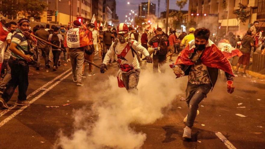 Manifestantes huyen de los gases lacrimógenos lanzados por la Policía en una protesta en Perú.