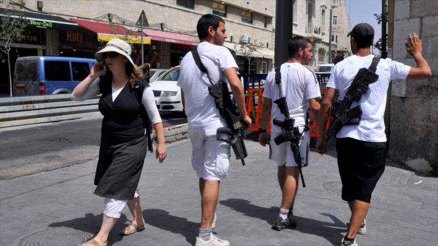 Colonos israelíes portando rifles de asalto M-16 y Tavor en una calle en Al-Quds (Jerusalén)