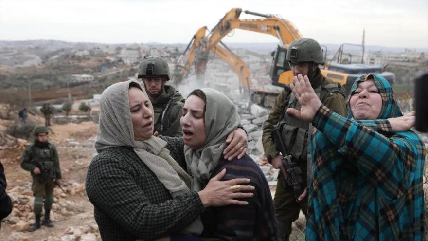 Los residentes palestinos reaccionan cuando su casa es demolida por las fuerzas israelíes en Al-Jalil (Hebrón), Cisjordania, 28 de diciembre de 2021.