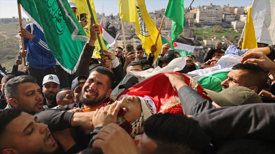 Los palestinos llevan el cuerpo de un joven palestino, asesinado por fuego israelí en medio de enfrentamientos, en Cisjordania, 27 de enero de 2023.