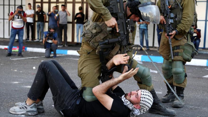 Un militar del régimen israelí arremete contra un palestino durante una protesta en Hebrón, Cisjordania.