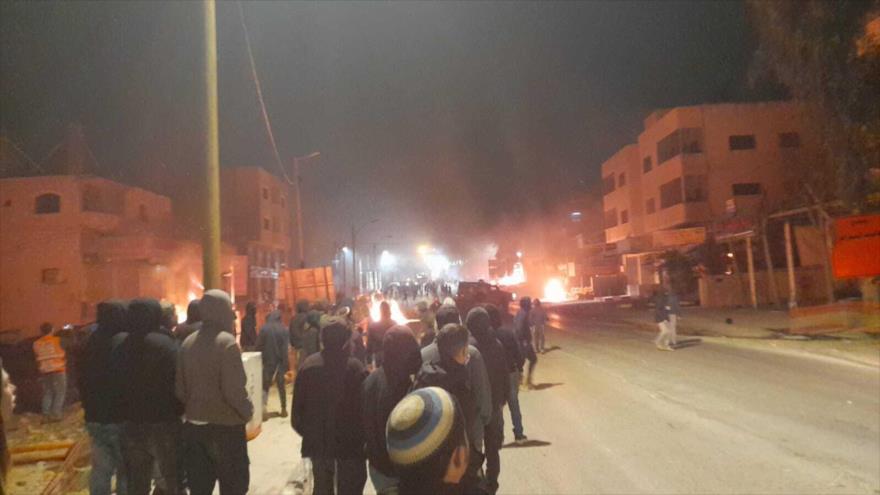 Colonos observan cómo se queman los automóviles y las casas en Huwara, Cisjordania, 26 de febrero de 2023.