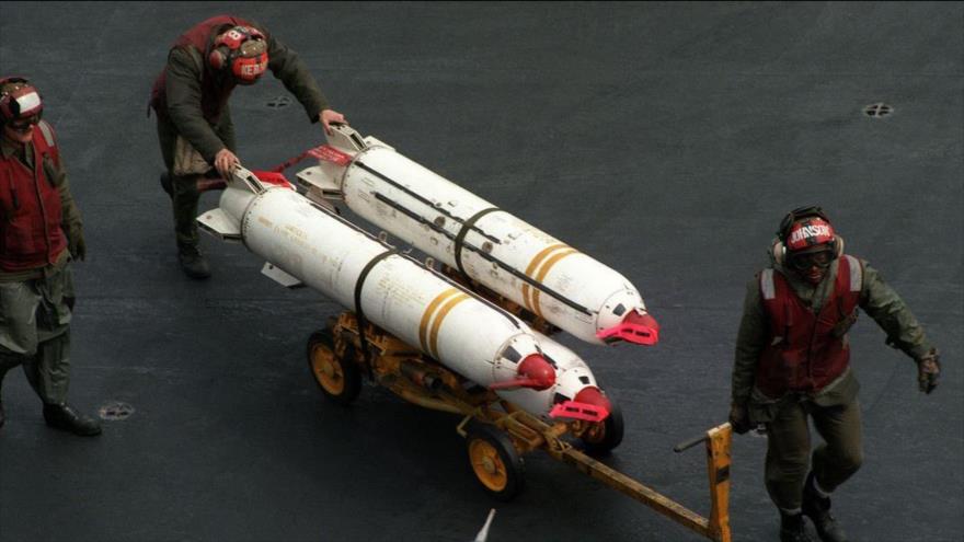 Tripulantes de mantenimiento de la Marina de los EE.UU. transportan tres bombas racimo MK-20. 