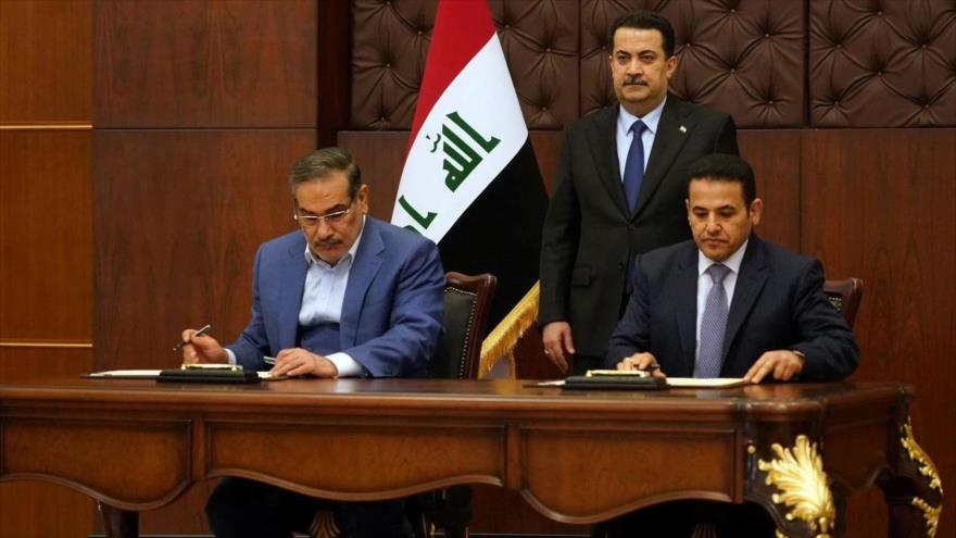 El secretario del Consejo Supremo de Seguridad Nacional de Irán (izda.) y su par iraquí firman el acuerdo en presencia del premier de Irak, 19 de marzo de 2023.