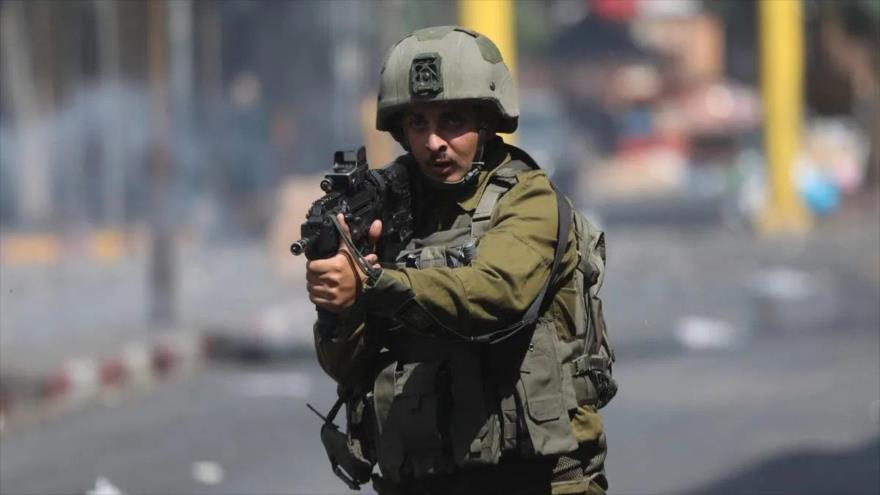 Un soldado israelí apunta su arma contra los manifestantes palestinos durante una protesta en Cisjordania, 9 de agosto de 2022.