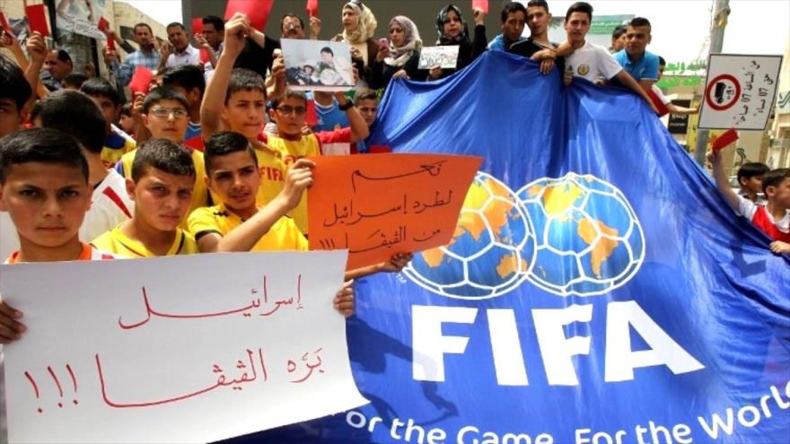 Jóvenes palestinos con pancartas que dicen “Israel fuera de la FIFA” en una protesta en la ciudad cisjordana de Hebrón, 28 de mayo de 2015. (Foto: AFP)