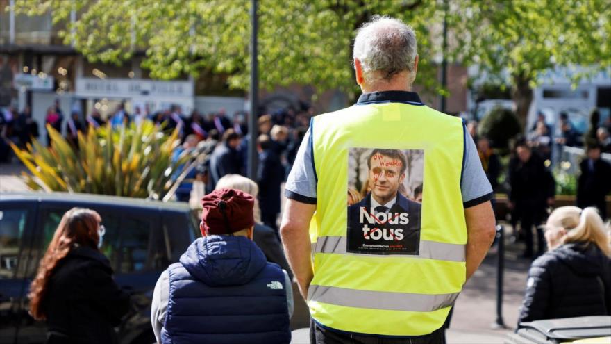 Manifestante del movimiento de los chalecos amarillos con una imagen contra el presidente de Francia, Emmanuel Macron. (Foto: AFP)