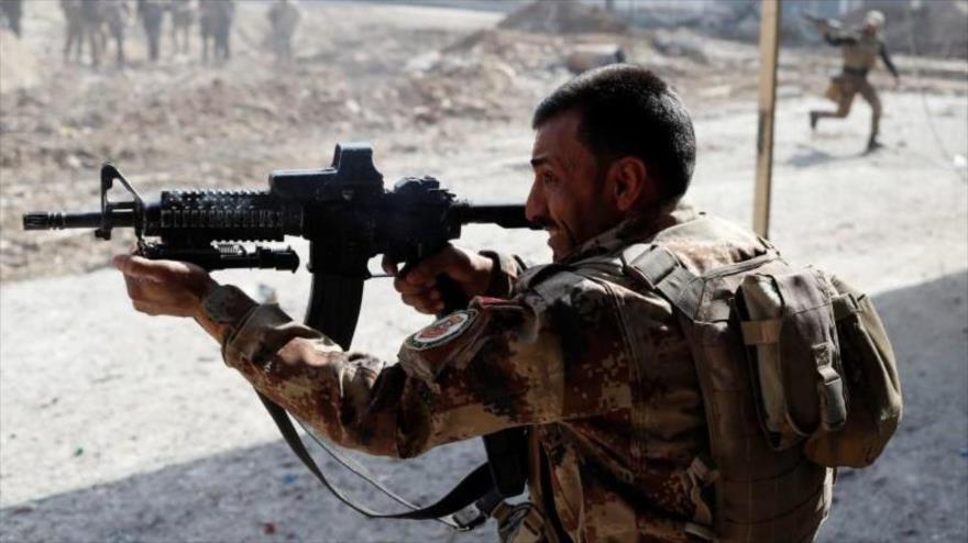 Un soldado de las fuerzas especiales iraquíes dispara con un rifle mientras otros soldados cruzan la calle durante una batalla en Mosul, Irak, 1 de marzo de 2017.
