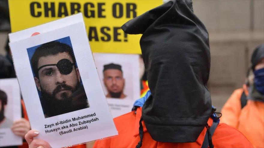 Un manifestante con una capucha negra sostiene un retrato del detenido Abu Zubaydah durante una protesta en Londres, 8 de enero de 2022.