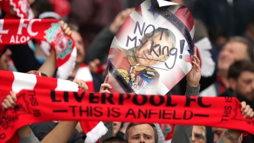 Los fanáticos del Liverpool sostienen un cartel que dice ‘No es mi rey’ mientras abuchean el himno nacional, 6 de mayo de 2023.
