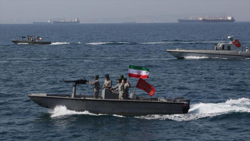 Fuerzas navales iraníes patrullan en las aguas territoriales en el Golfo Pérsico, mientras se ven petroleros al fondo.