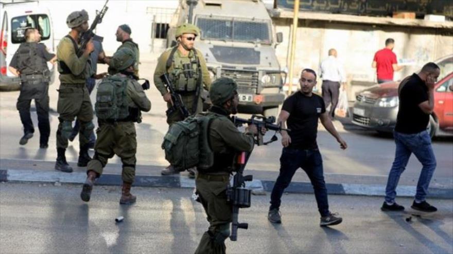 Soldados israelíes están estacionados frente a una tienda palestina en Cisjordania, 25 de mayo de 2022. (Foto: Reuters)