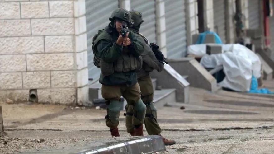 Un soldado israelí apunta con su pistola a los manifestantes palestinos, en Nablus, en Cisjordania, 19 de marzo de 2023. (Foto: EFE)