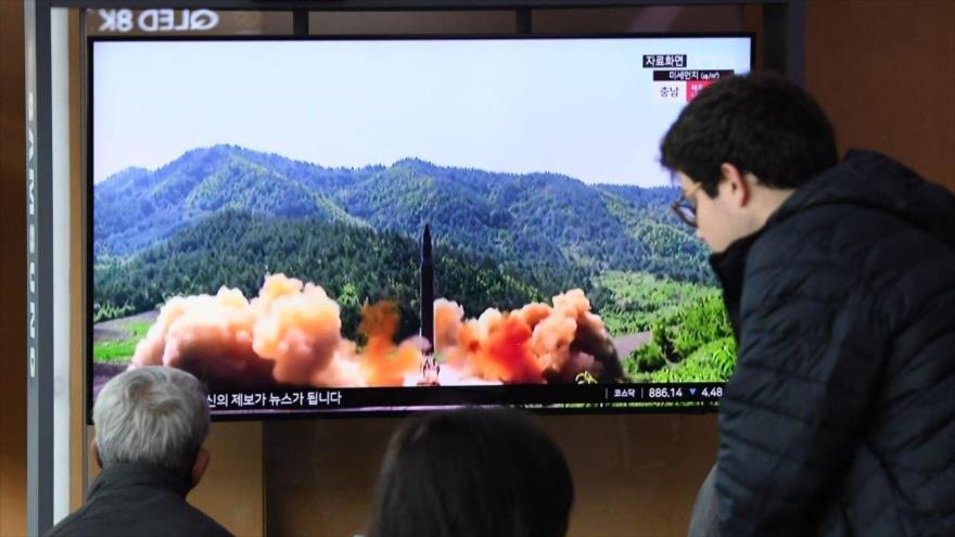 La gente mira imágenes de una prueba de misiles de Corea del Norte, en una estación de tren en Seúl, 13 de abril de 2023.