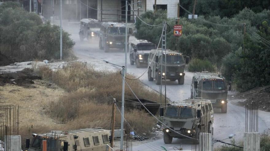 Un convoy de vehículos del ejército es visto durante su agresión militar en el campo de refugiados de Yenín, en la Cisjordania ocupada, 4 de julio de 2023. (Foto AP)
