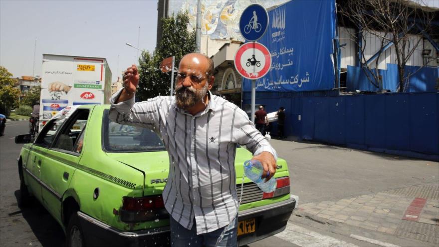 Un taxista iraní se echa agua en la cara para refrescarse en Teherán, la capital.