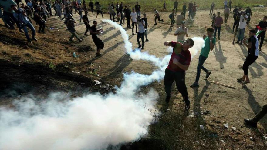 Palestinos en medio de gases lacrimógenos lanzados por fuerzas israelíes en Gaza.