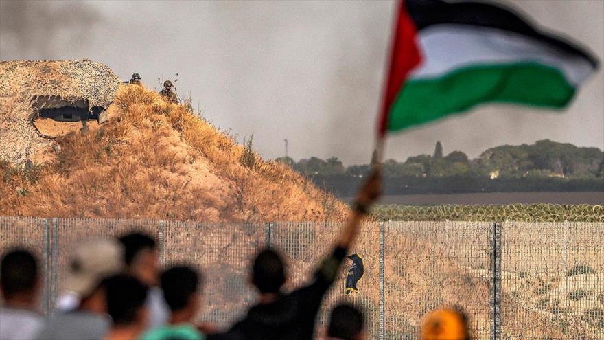 Soldados israelíes miran detrás de un búnker a los palestinos que se manifiestan cerca de la valla fronteriza en Gaza, 18 de mayo de 2023. (Foto: AFP)