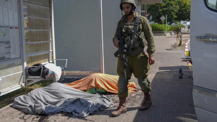 Un soldado israelí junto a los cuerpos de israelíes muertos por ataques con cohetes lanzados desde la Franja de Gaza, en la ciudad de Sderot, 7 de octubre de 2023.