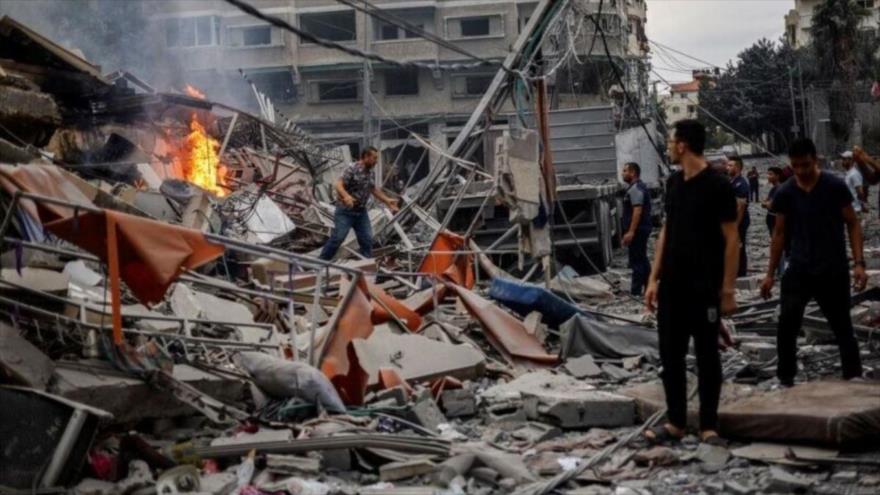 Palestinos observan un incendio entre los escombros de un edificio residencial dañado, tras los ataques israelíes contra Gaza, 10 de octubre de 2023. (Foto: Reuters)
