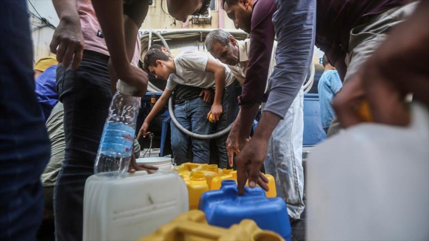 Palestinos llenan contenedores con agua potable desde un vehículo de distribución de agua en Gaza, 12 de octubre de 2023. (Foto: AP)