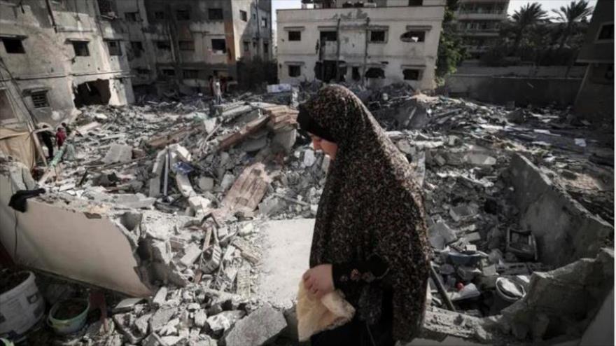 Una mujer palestina camina entre los escombros de un edificio derribado por israel. (Foto: AFP)