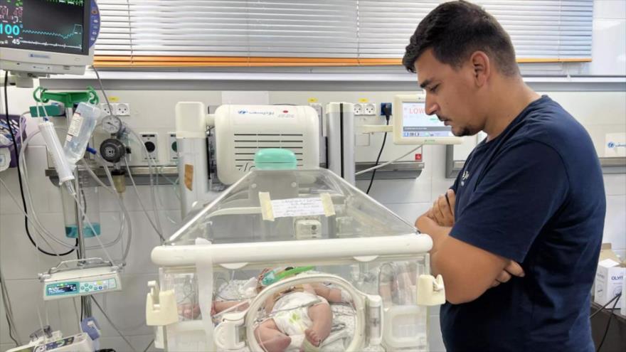 Ayman Abu Shamalah, mira a la incubadora donde se encuentra su hija, recién nacida por cesárea del vientre sin vida de su madre.
