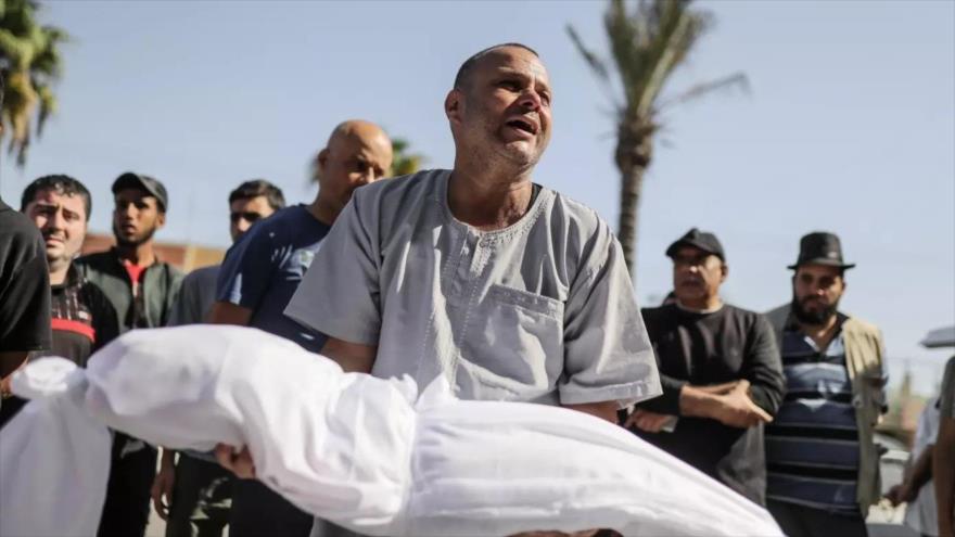 Un miembro de la familia lleva el cuerpo envuelto de un niño muerto en ataques aéreos israelíes, Gaza, 15 de octubre de 2023 (Foto: Reuters)