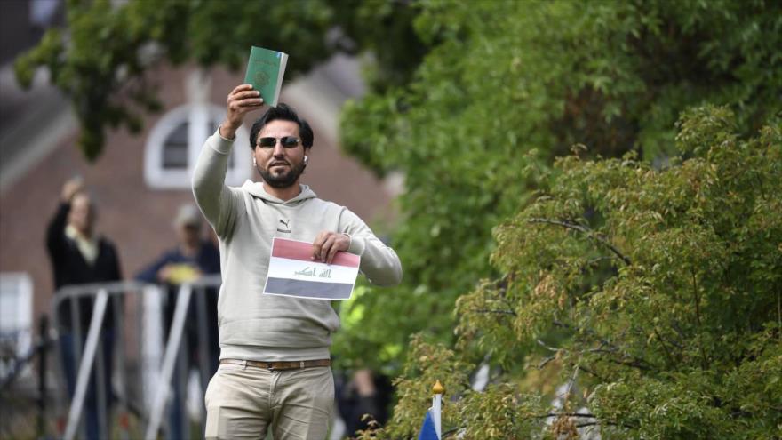 Salwan Momika sostiene una copia del Corán y una bandera iraquí frente a la embajada de Irak en Estocolmo, 20 de julio de 2023. (Fuente: AFP)