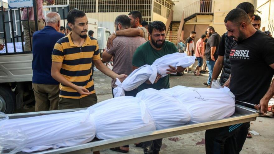 Palestinos trasladan los cadaveres de los civiles asesinados en ataques israelíes al cementerio en Gaza, octubre de 2023.