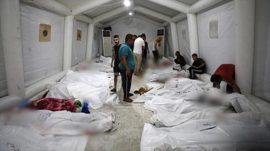 Personas observan los cuerpos de los palestinos muertos tras una explosión en el hospital Al Ahli en el centro de Gaza, 18 de octubre. (Foto: AFP)