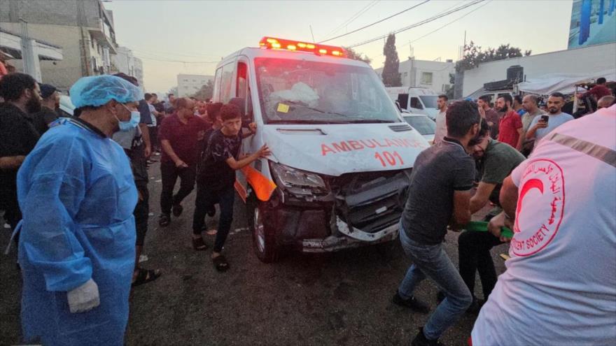 Palestinos empujan una ambulancia luego de que un convoy de ambulancias fuera atacado por Israel cerca de la entrada del hospital Al-Shifa, ubicado en la Ciudad de Gaza.