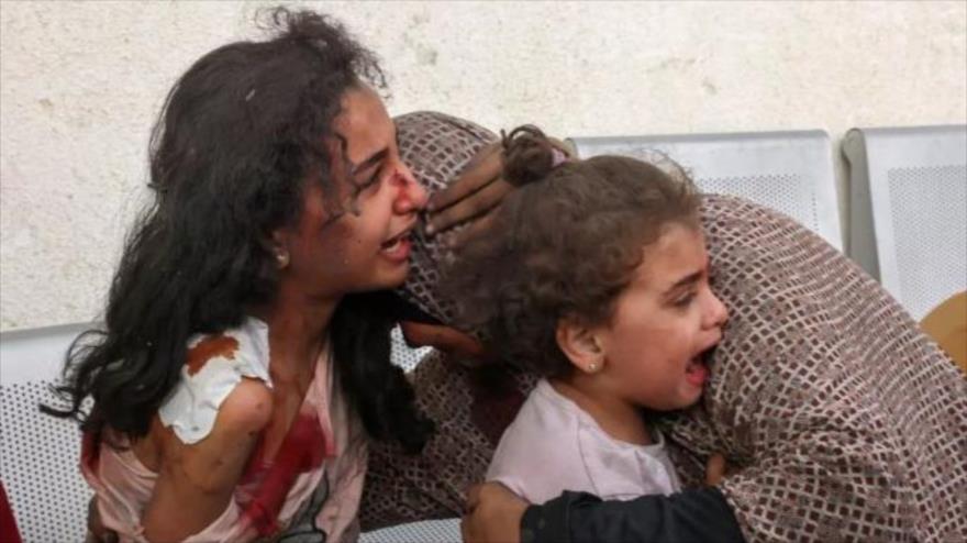 Una mujer palestina junto a sus hijas mientras esperan en el hospital de la ciudad de Rafah, en el sur de la Franja de Gaza, 12 de octubre de 2023 (AFP) 