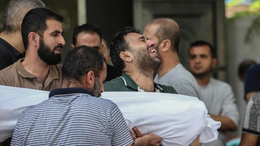 Afuera de la morgue del hospital Al-Shifa, en Gaza, un hombre llora mientras lleva el cuerpo de una de las víctimas de los ataques aéreos israelíes, octubre de 2023. (Foto: AP)