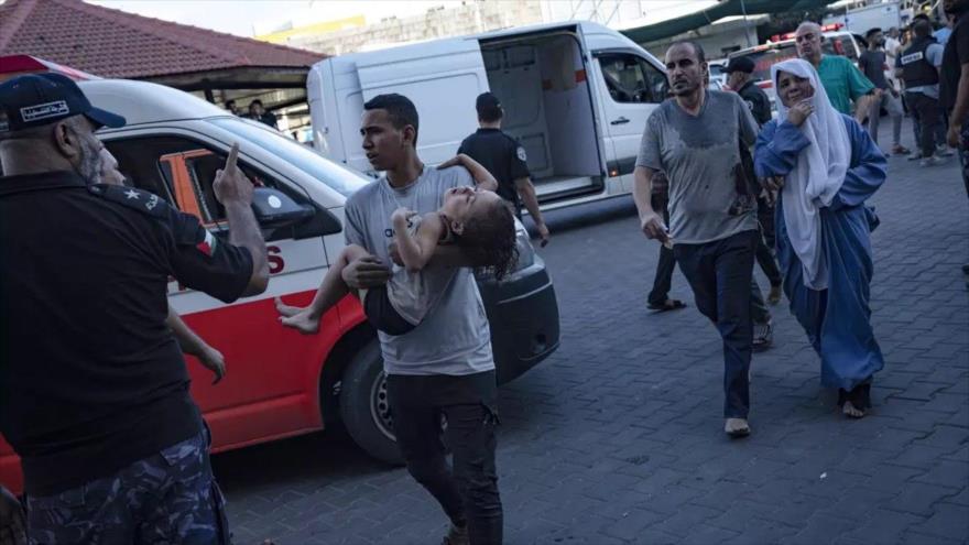 Un palestino lleva a una niña herida tras un ataque israelí al hospital Al-Shifa en la ciudad de Gaza, octubre de 2023. (Foto: AP)