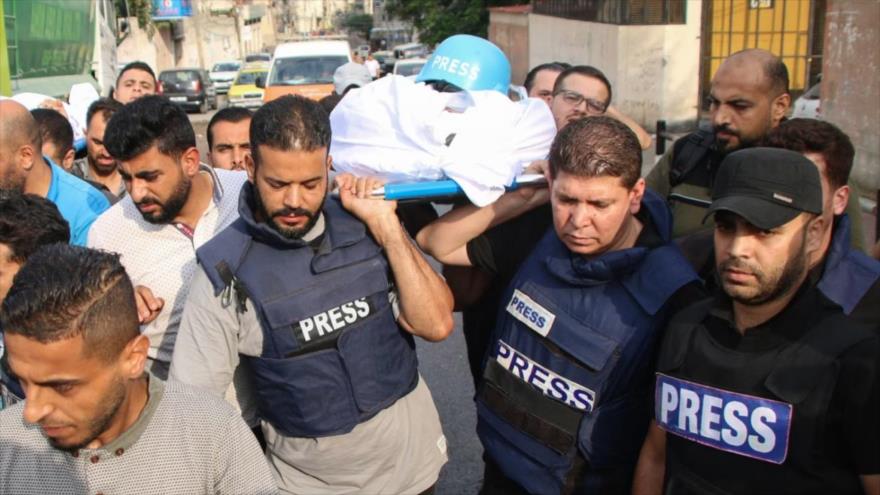 Familiares y colegas llevan el cuerpo de un periodista matado en Gaza por los bombardeos israelíes.