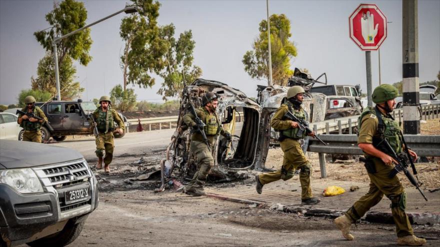 Se ven soldados israelíes junto a automóviles quemados cerca de la entrada del Kibbutz Beeri, en el sur de los territorios ocupados palestinos, 9 de octubre de 2023. (Foto: Flash90)