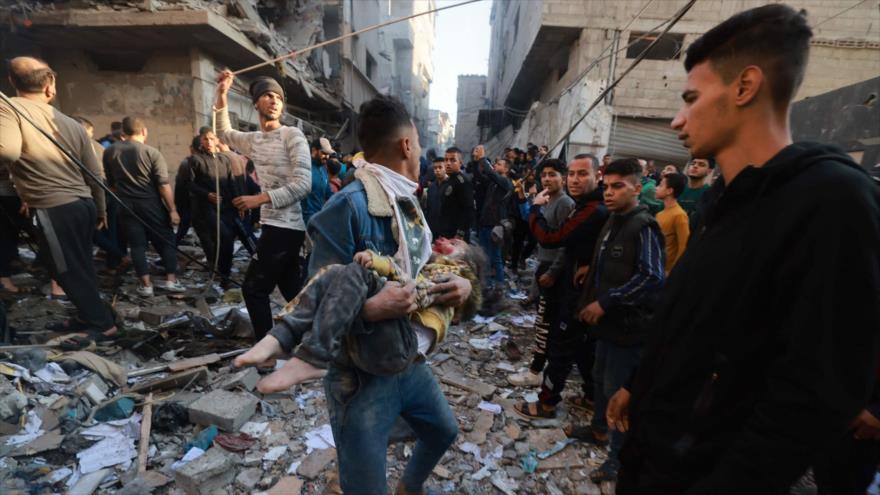 Un joven palestino lleva a un niño herido tras un bombardeo israelí en Rafah, 1 de diciembre de 2023. (Foto: AFP)