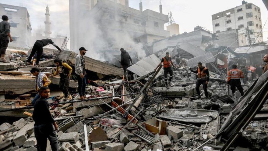 Ciudadanos palestinos y rescatistas inspeccionan la destrucción causada por los ataques aéreos israelíes en Jan Younis,4 de diciembre de 2023. (Foto de Getty Images)