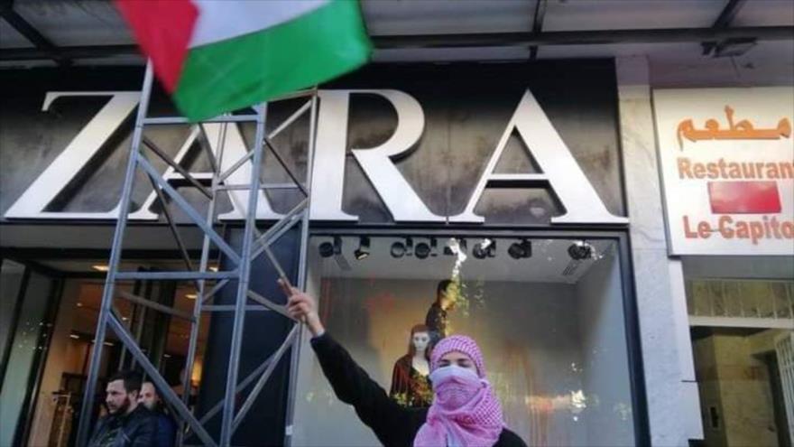 Una mujer tunecina lleva una bandera de Palestina ante una sucurral de empresa española de textil, 11 de diciembre 2023.
