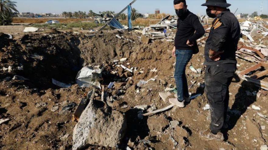 Dos miembros de las fuerzas iraqués inspeccionan el lugar de un ataque aéreo estadounidense en Al-Hilla, Irak, 26 de diciembre de 2023. 