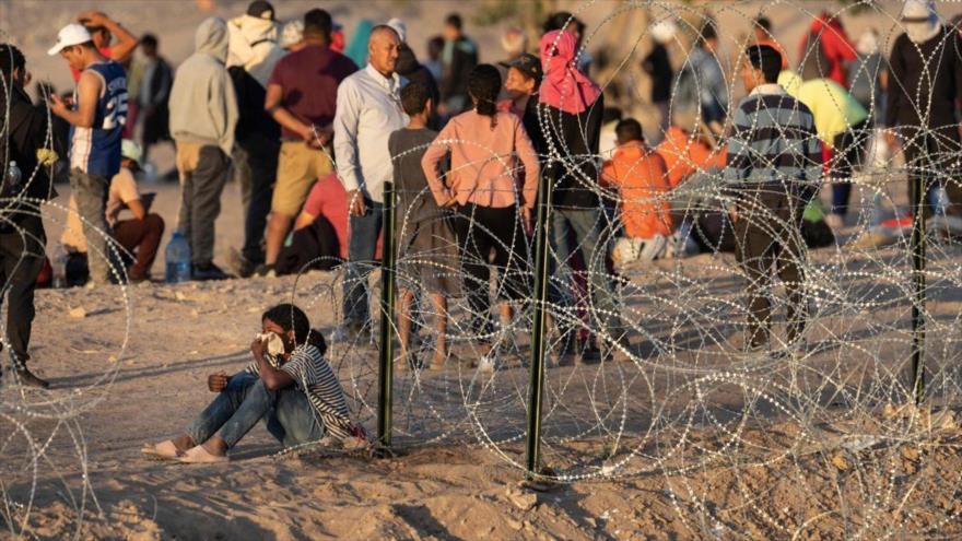 Un grupo de inmigrantes aguardan junto a la frontera tras cruzar desde México. 
