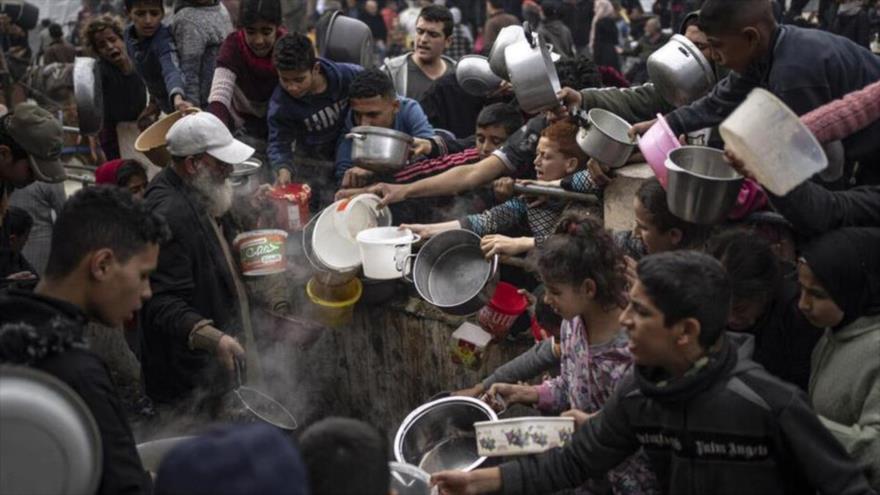 Ciudadanos palestinos en la bloqueada Franja de Gaza esperan recibir comida.